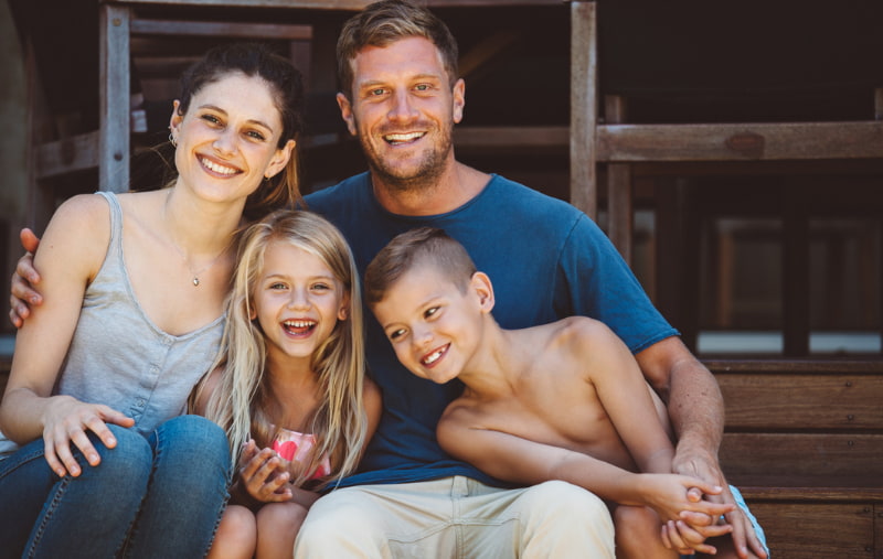 Casual family portrait on the steps of their backyard.