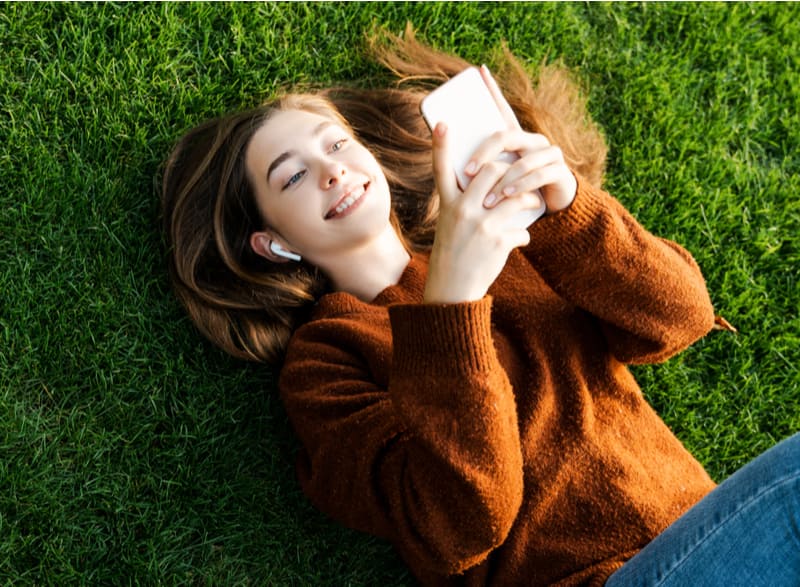 Smiling happy teenager girl looking at her smart cell phone