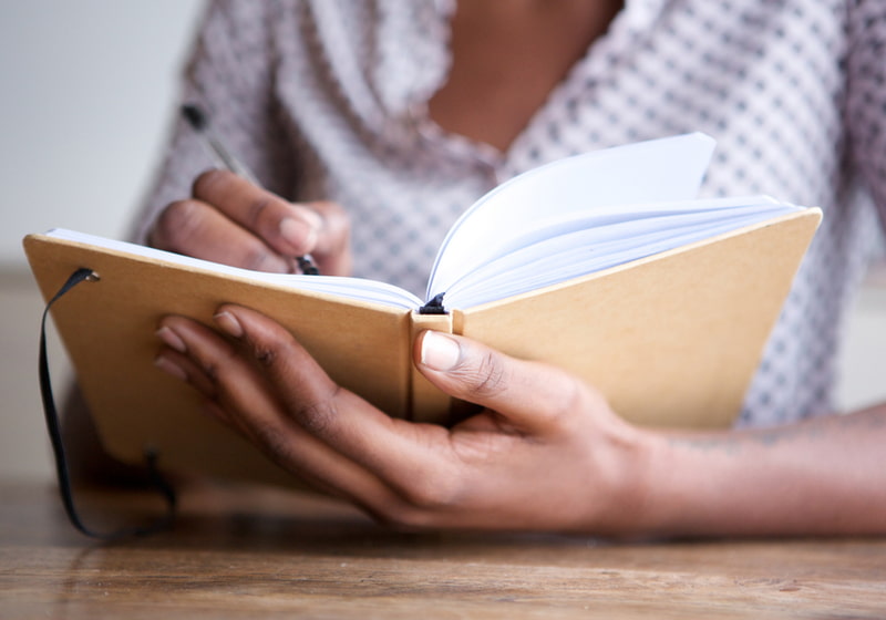 Female author at home writing in journal