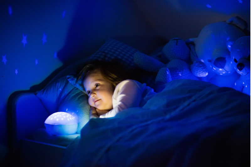 Dark bedroom with night light projecting stars on room