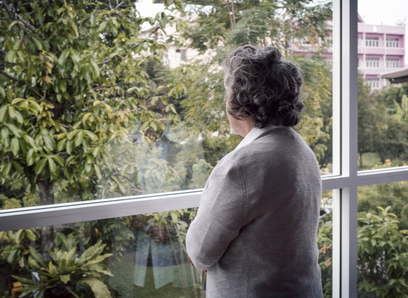 A serious senior woman looking at the window