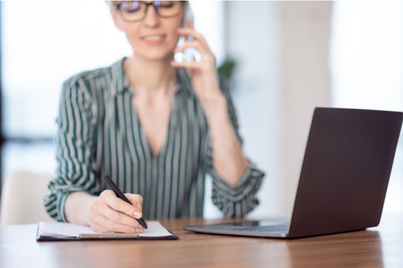 Businesswoman talking on cellphone and taking notes