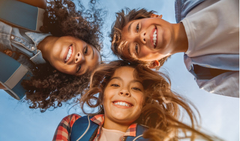 Portrait of smiling school kids standing circle at the field