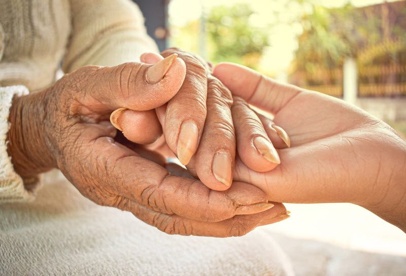 Hand of an old woman holding the hand of a young girl