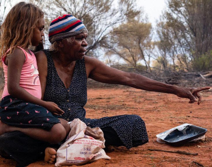 Aboriginal old woman and little girl sitting on a bush