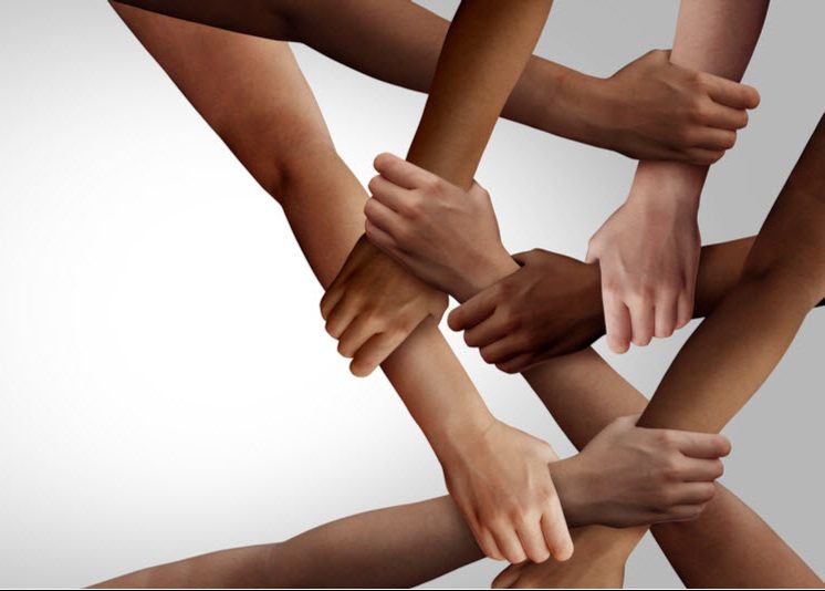 teamwork as a group of diverse people holding arms