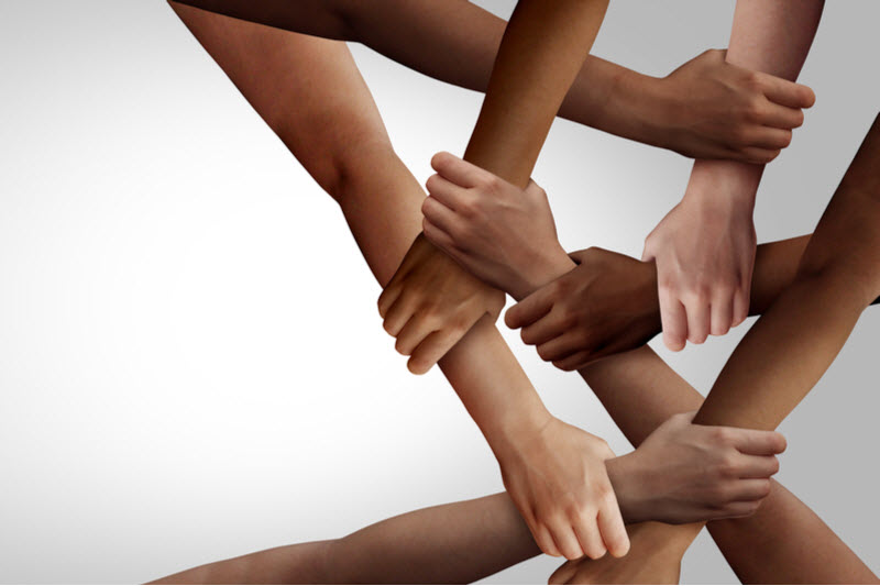 teamwork as a group of diverse people holding arms