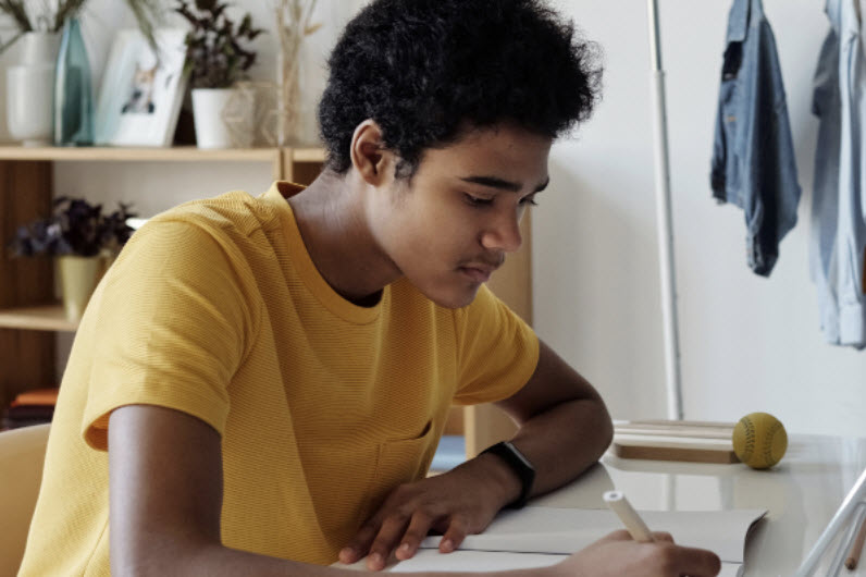 A boy studying and writing on his desk at home